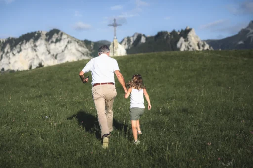 Un grand-père et sa petite fille qui courent main dans la main dans une prairie. Photo du photographe Rüdi Welter. Un grand-père et sa petite fille qui courent main dans la main dans une prairie. Photo du photographe Rüdi Welter.